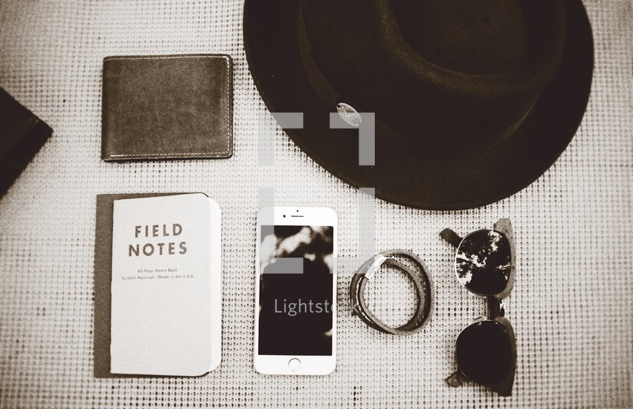 hair ties, sunglasses, wallet, field notes, notebook, table, cellphone, phone, hat