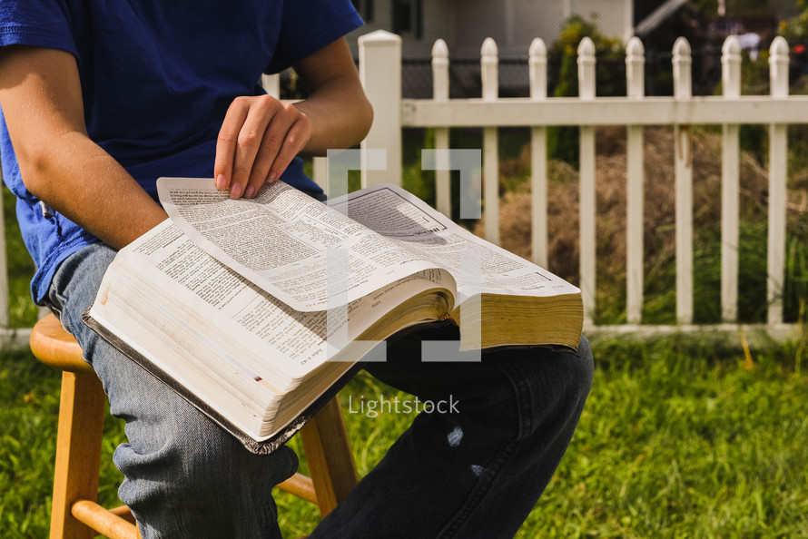 boy reading a Bible outdoors 