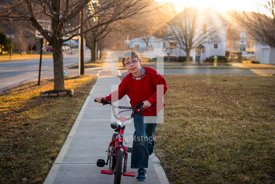 a boy riding a bike on a sidewalk 