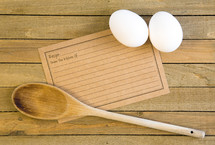 recipe card, wooden spoon and eggs