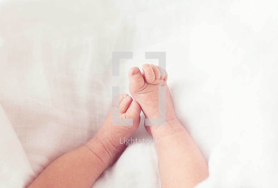 A baby's feet on a white blanket.
