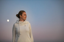 woman in a sweatshirt standing outdoors at dusk 