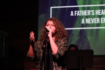 a woman singing into a microphone at a worship service 