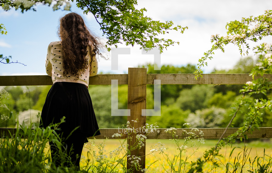 a teen girl looking over a fence