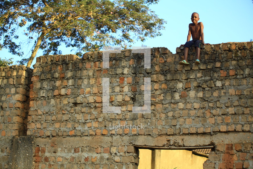 boy child sitting on a brick wall