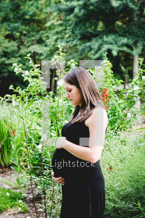 side profile of a pregnant woman holding her belly 