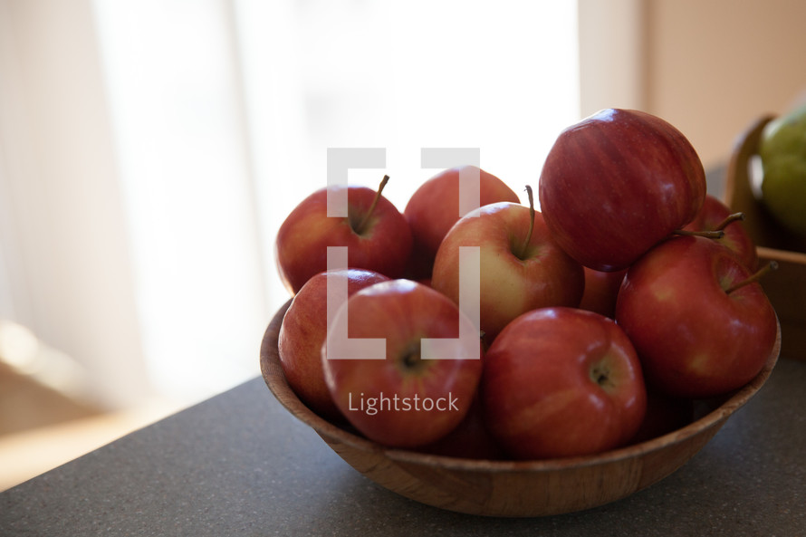 A bowl of red apples on a countertop.