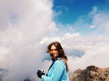 Woman in the clouds on a mountaintop.