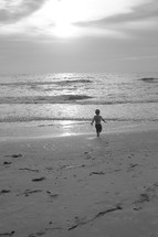 Boy running on the beach at sunset.