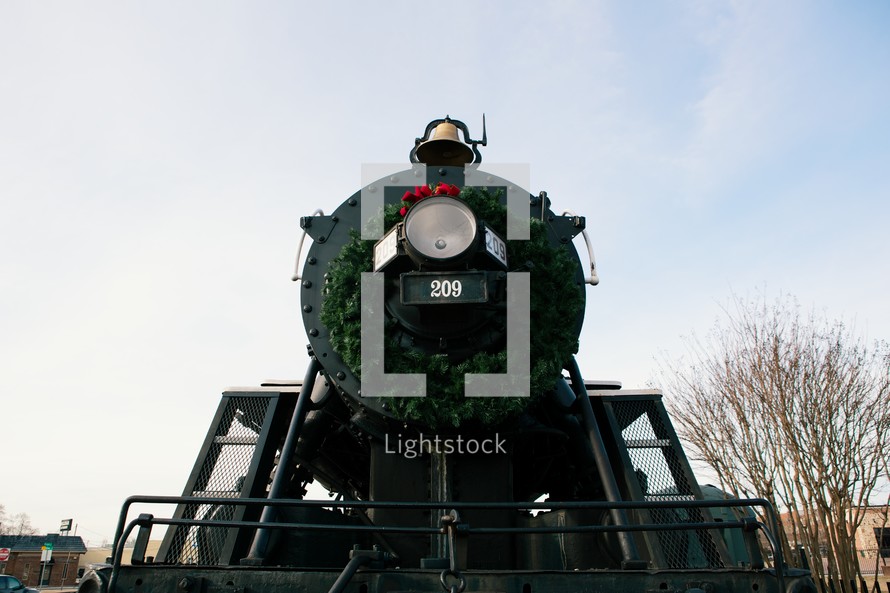 A christmas wreath on the front of a train engine. 