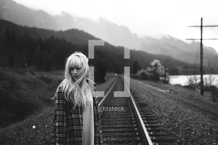 woman standing on railroad tracks 