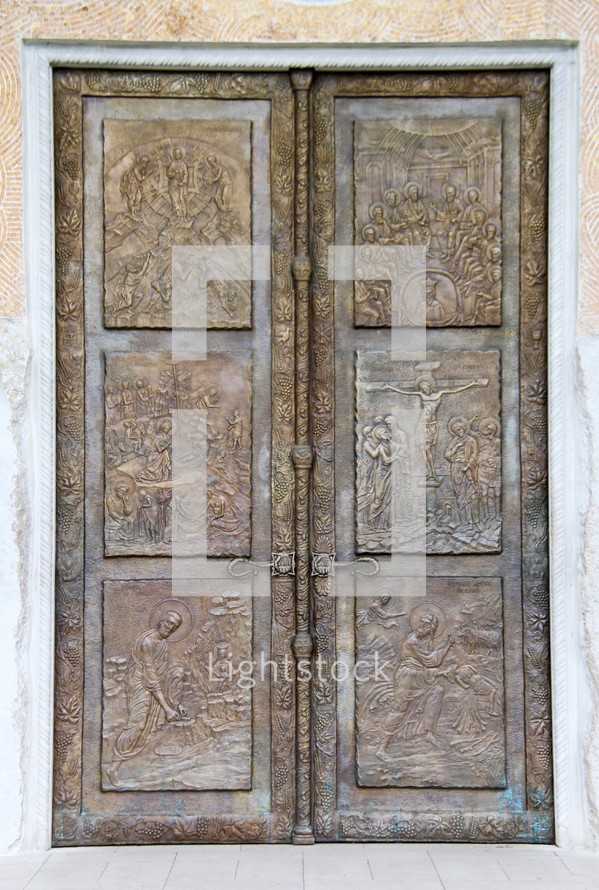 Ornate metal doorway of the Podgorica Orthodox Cathedral, Montenegro with panels depicting scenes from the Bible.