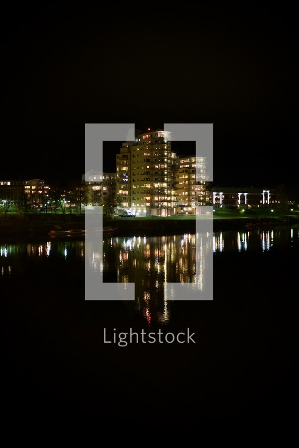 reflection of a building with glowing lights at night on water 