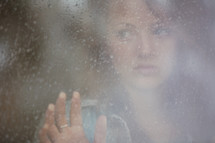 Woman looking out a frosted window pane.