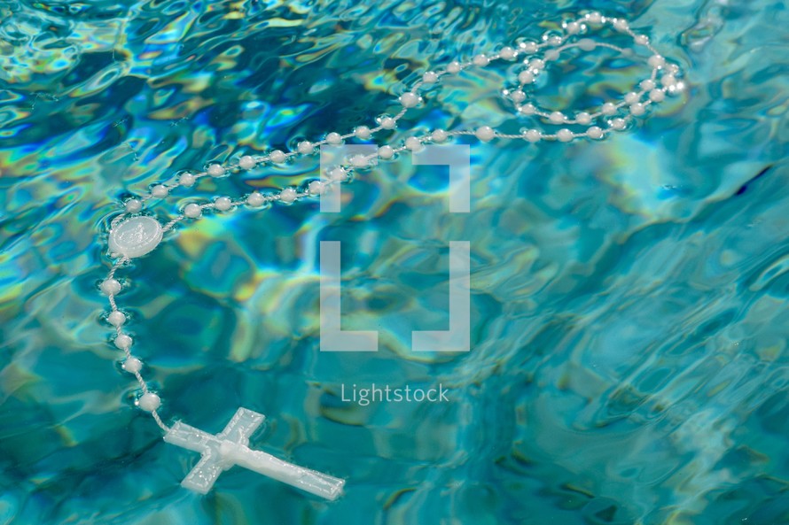 a rosary floating on turquoise water 