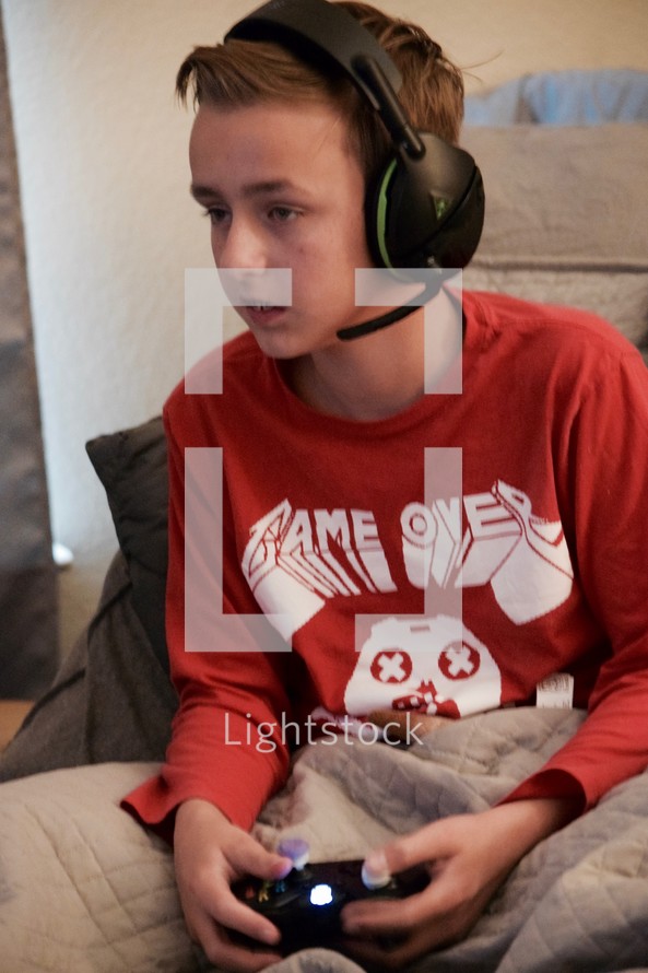 a teen boy zoned out playing video games with a headset 