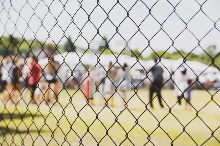 view of people through a chain link fence 