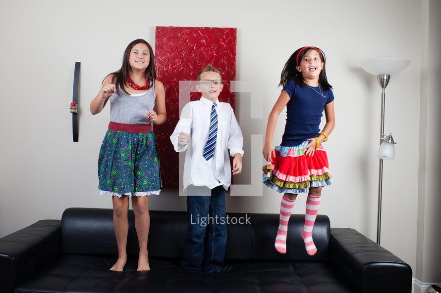 siblings jumping on a couch 