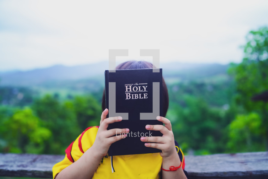 Happy little girl holding up Bible