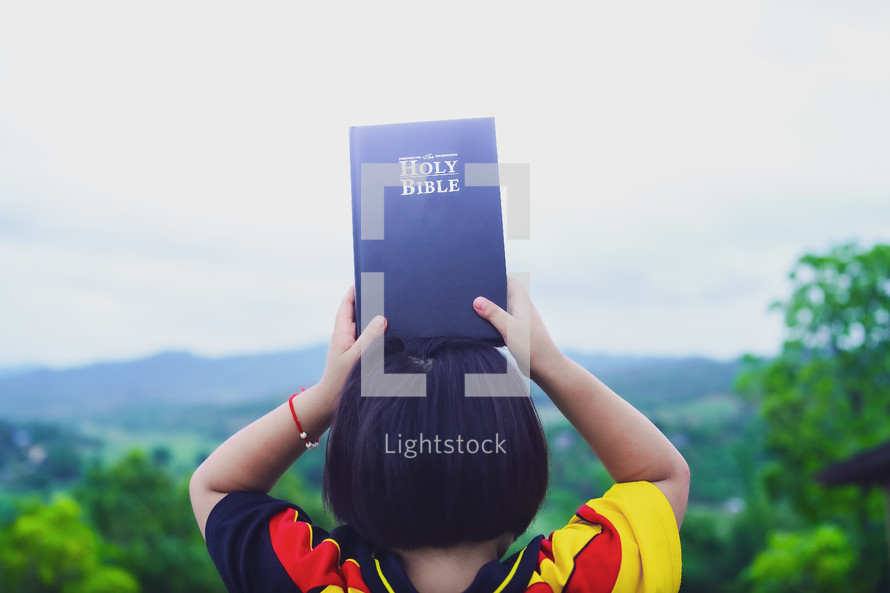 Happy little girl holding up Bible