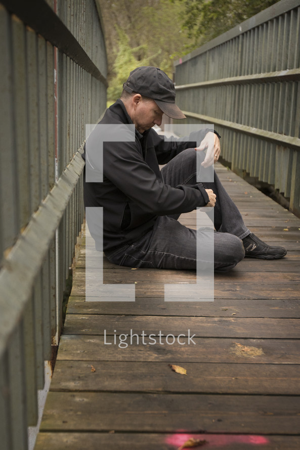 a man sitting on a boardwalk thinking