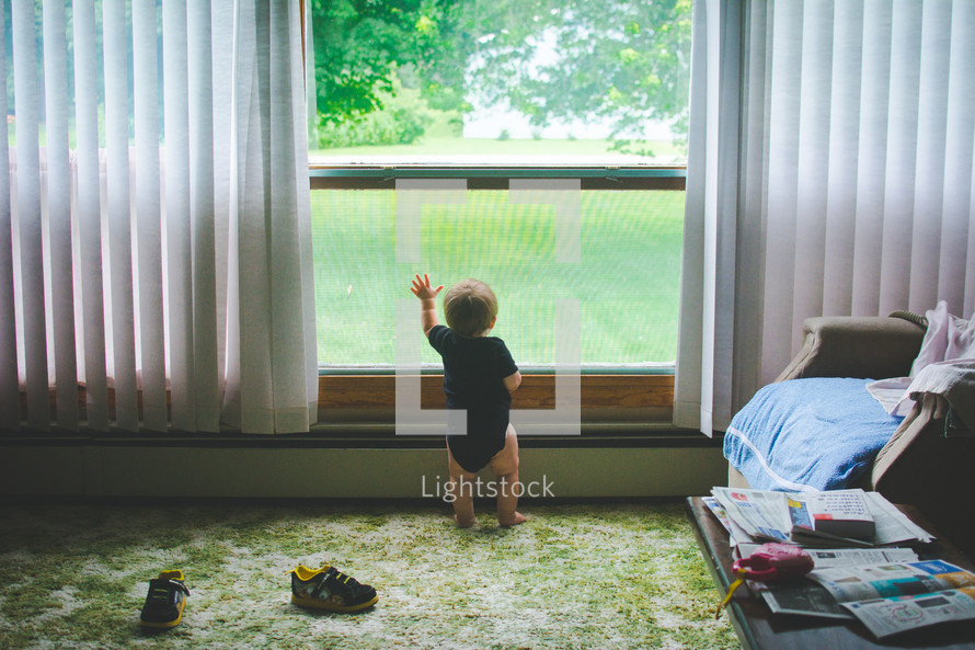 an infant boy looking out a window 
