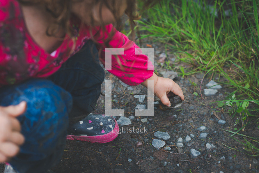 a girl picking up rocks in the dirt 