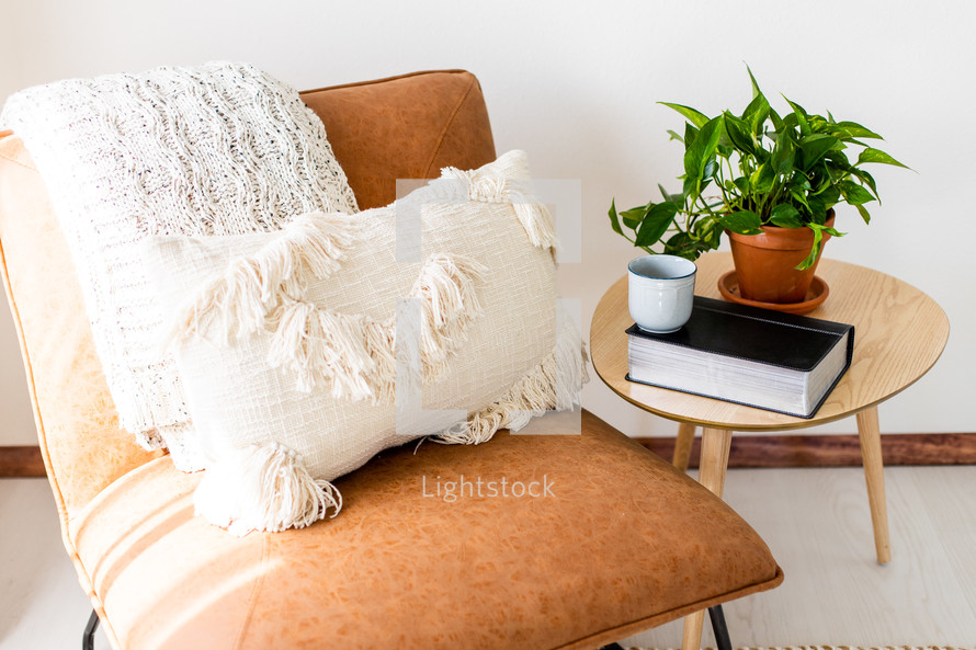 throw pillows on a chair and Bible on an end table 