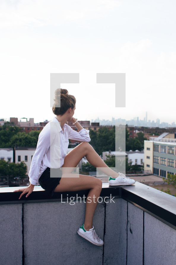 a woman sitting on a balcony railing looking out at the view 