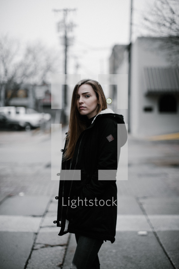a young woman walking down a street and stopping to look at the camera 
