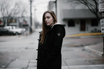 a young woman walking down a street and looking back at the camera 