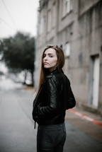 A young woman walking down a street looking back at the camera