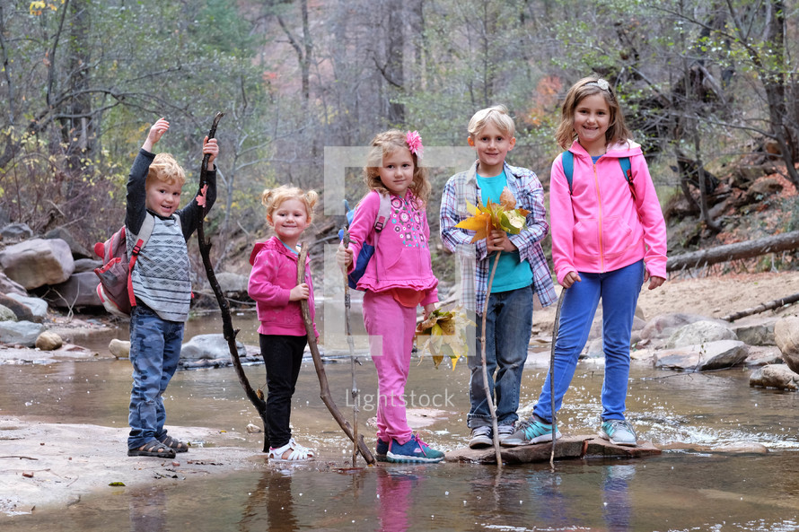 kids standing together outdoors in a stream 