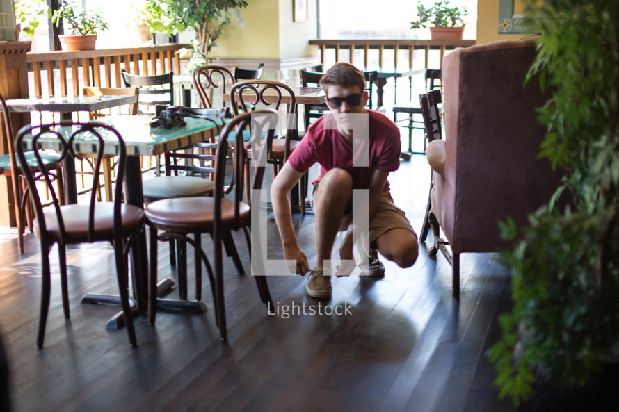 Teen tying his shoe in a cafe.