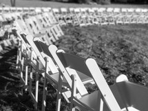 rows of white folding chairs for an outdoor wedding 