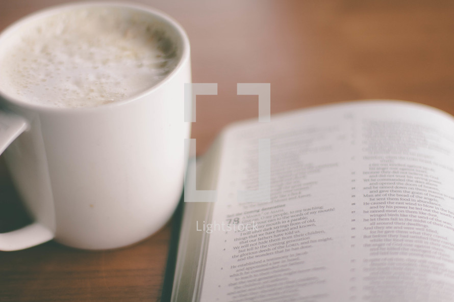 Coffee cup and open Bible on a table.