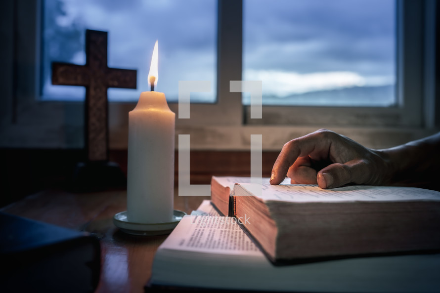 Person reading a Bible with candlelight