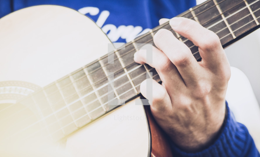 hands on the neck of a guitar 