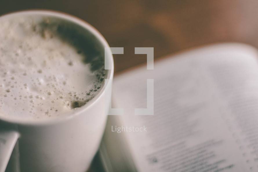 Cup of coffee and open Bible on a table.