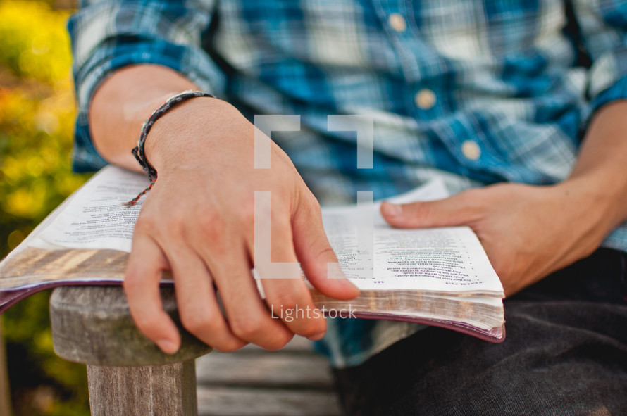a man sitting on a bench reading a Bible 