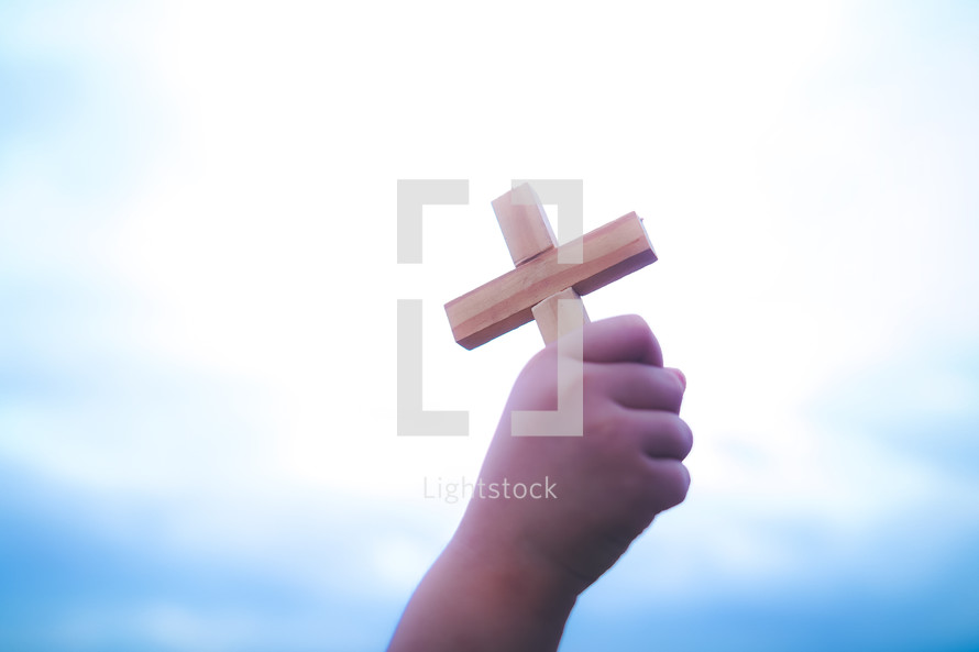 Hand holding a wooden cross up to the sky