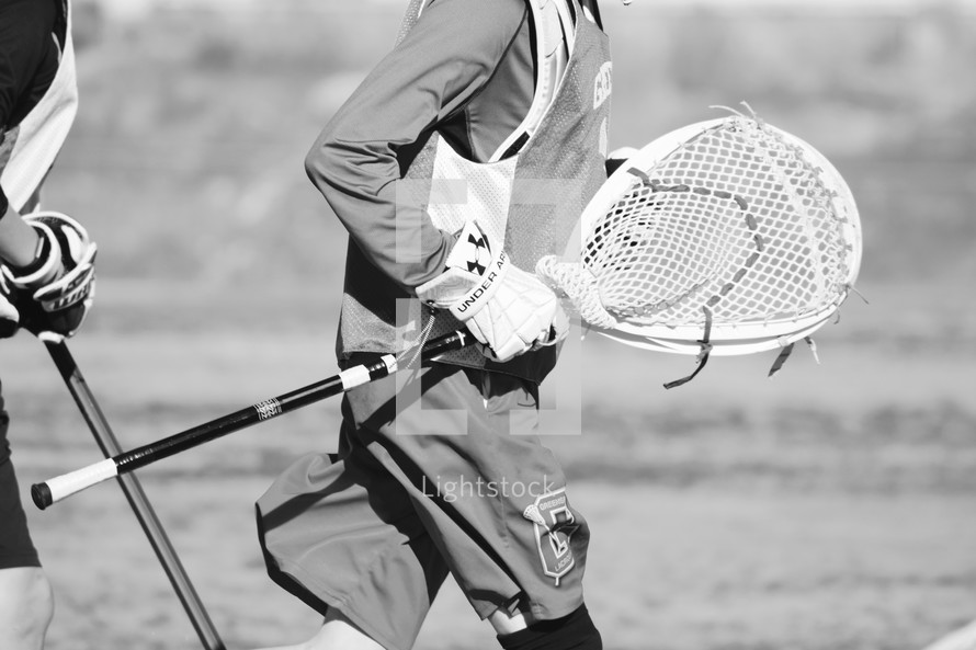 goalie carrying his stick on a boys Lacrosse team 