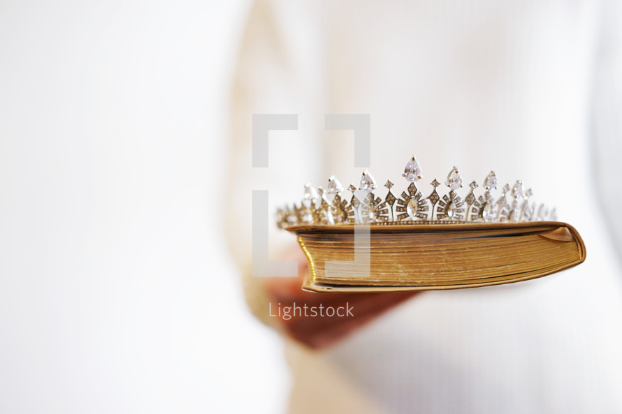 a woman holding a tiara and a Bible 