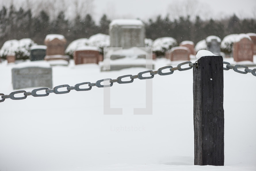 chain on a fence and graveyard in snow 