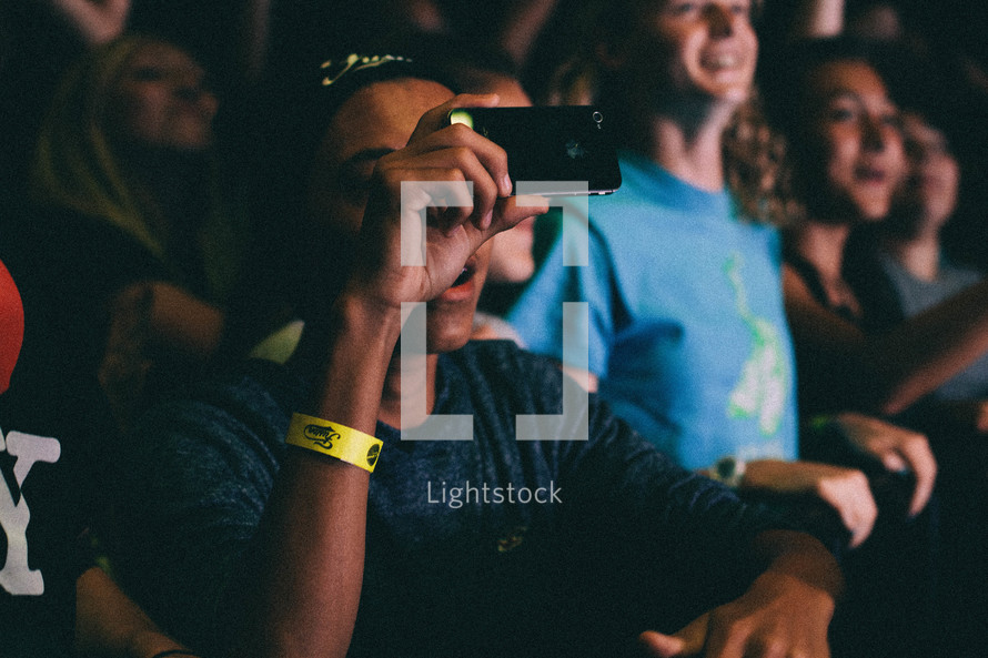 teens in an audience taking pictures with cellphones 