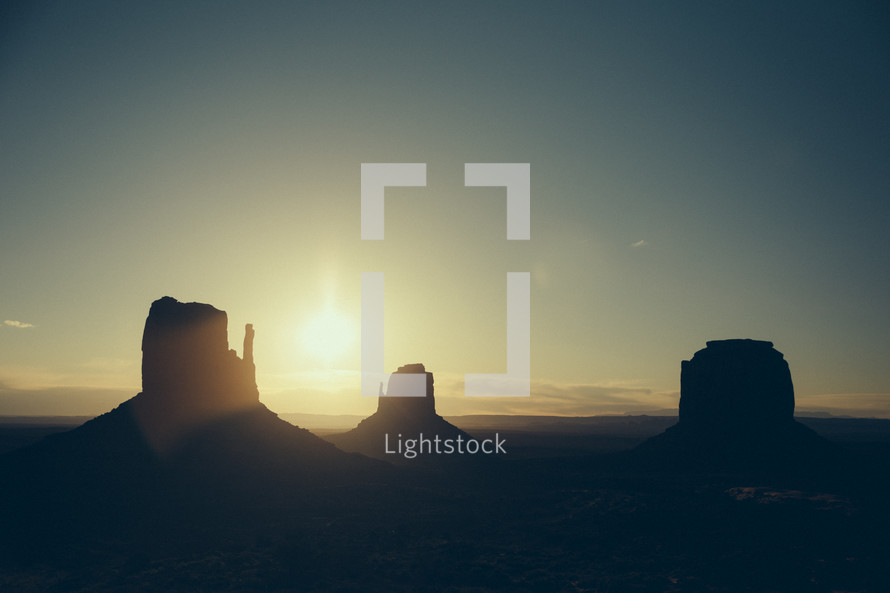 Silhouettes of buttes at sunset.