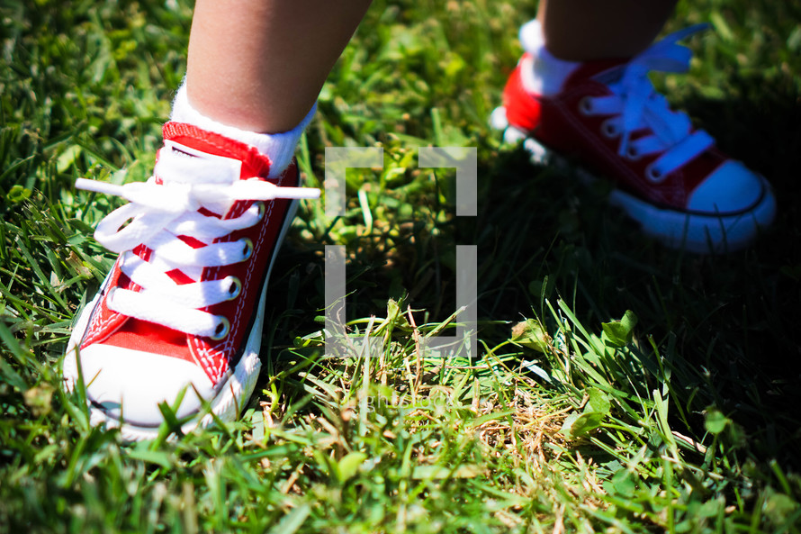 red sneakers on a toddler standing in the grass 