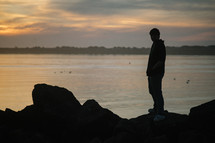 silhouette of a man at the shore at sunset 