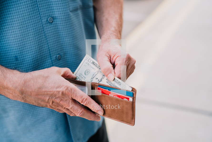 man pulling cash out of his wallet 