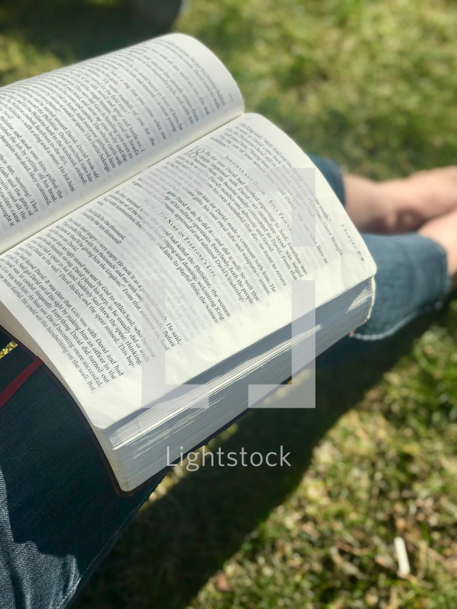reading a Bible sitting in the grass